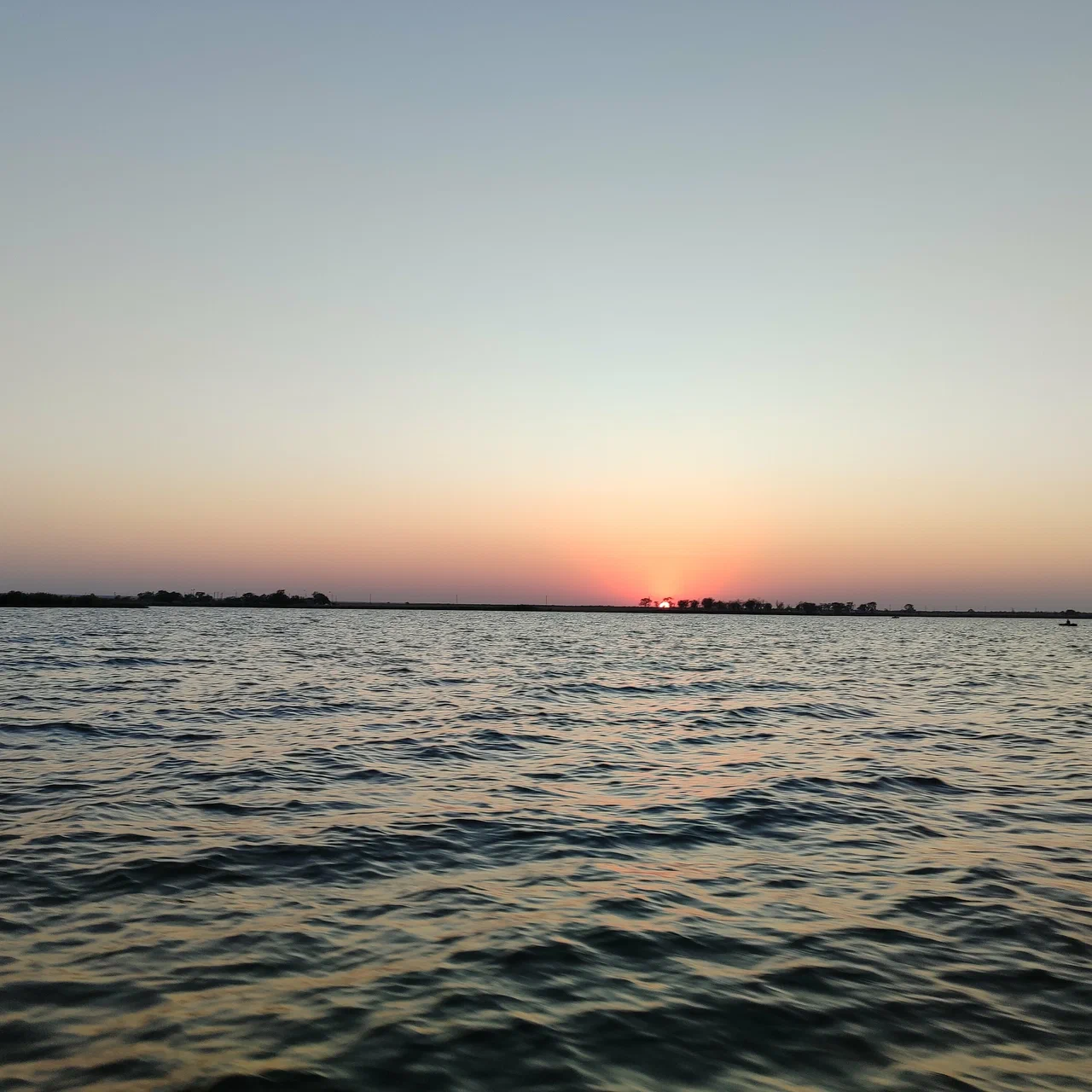 Рыбак на спокойном водоёме на рассвете